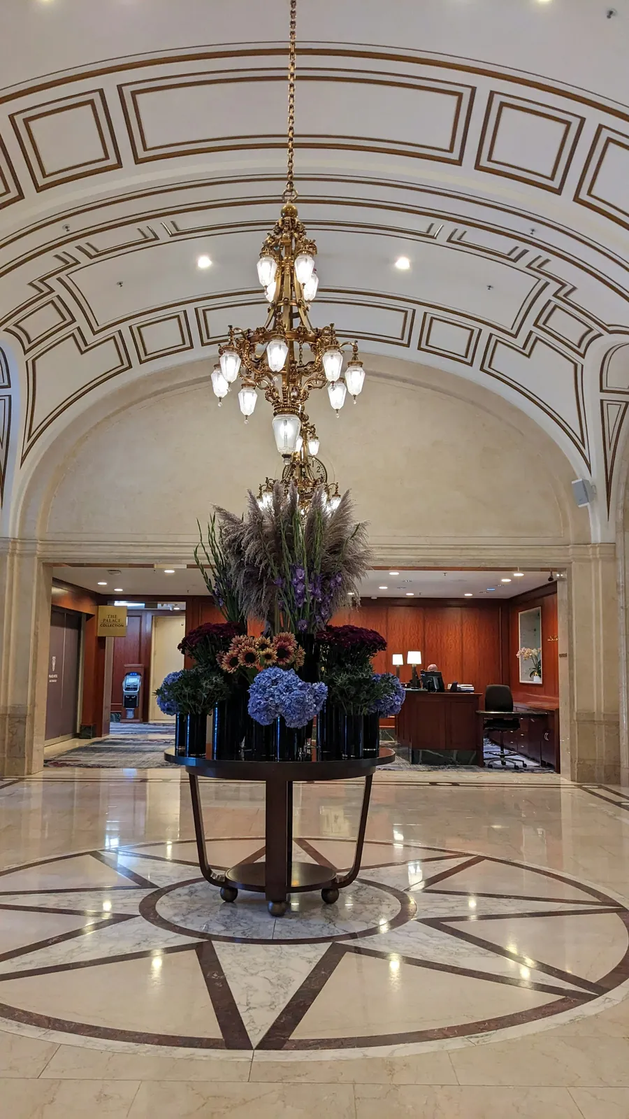 Polished marble lobby with a chandelier and floral arrangement